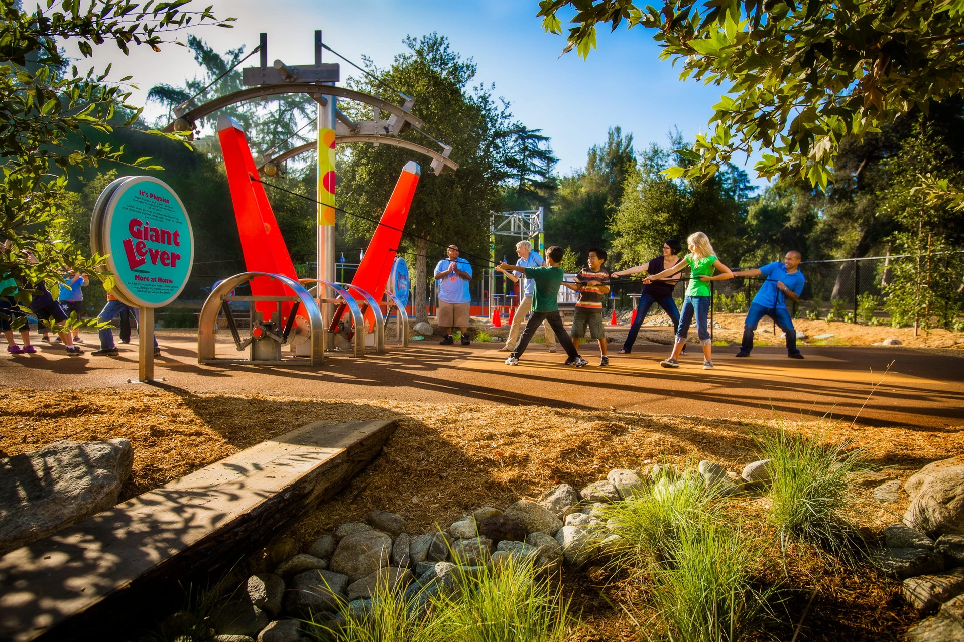 Kids pull a giant lever in an exhibit outside at Kidspace Museum.