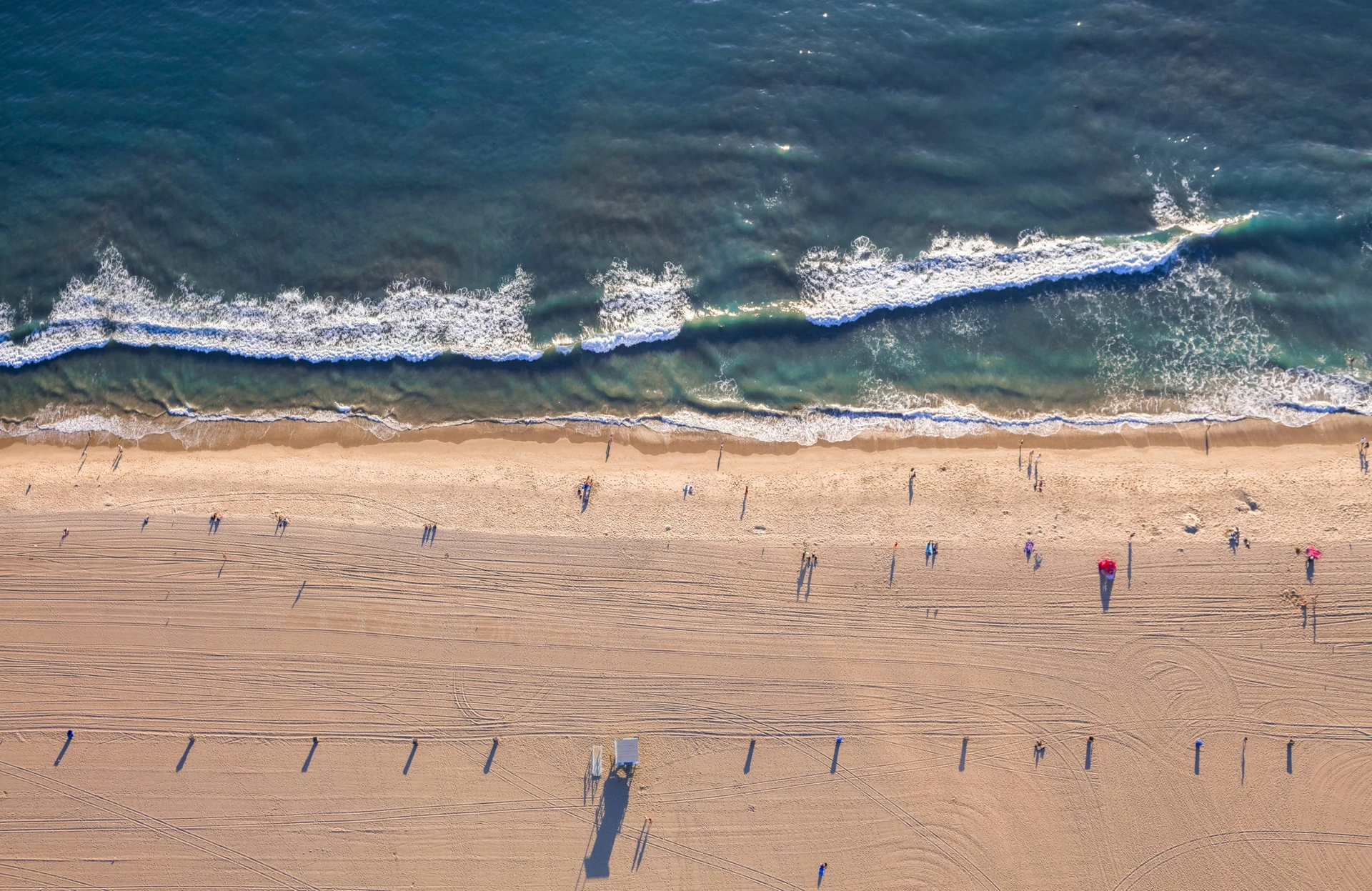 Aerial view looking down on Santa Monica beach near sunset.