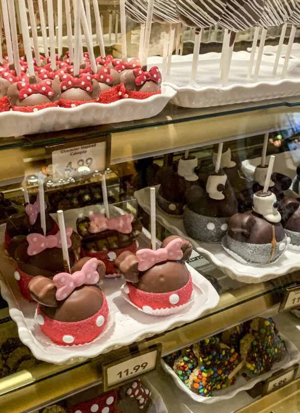 Candy apples shaped like Minnie Mouse and other adorable desserts inside of a display case at Disneyland.