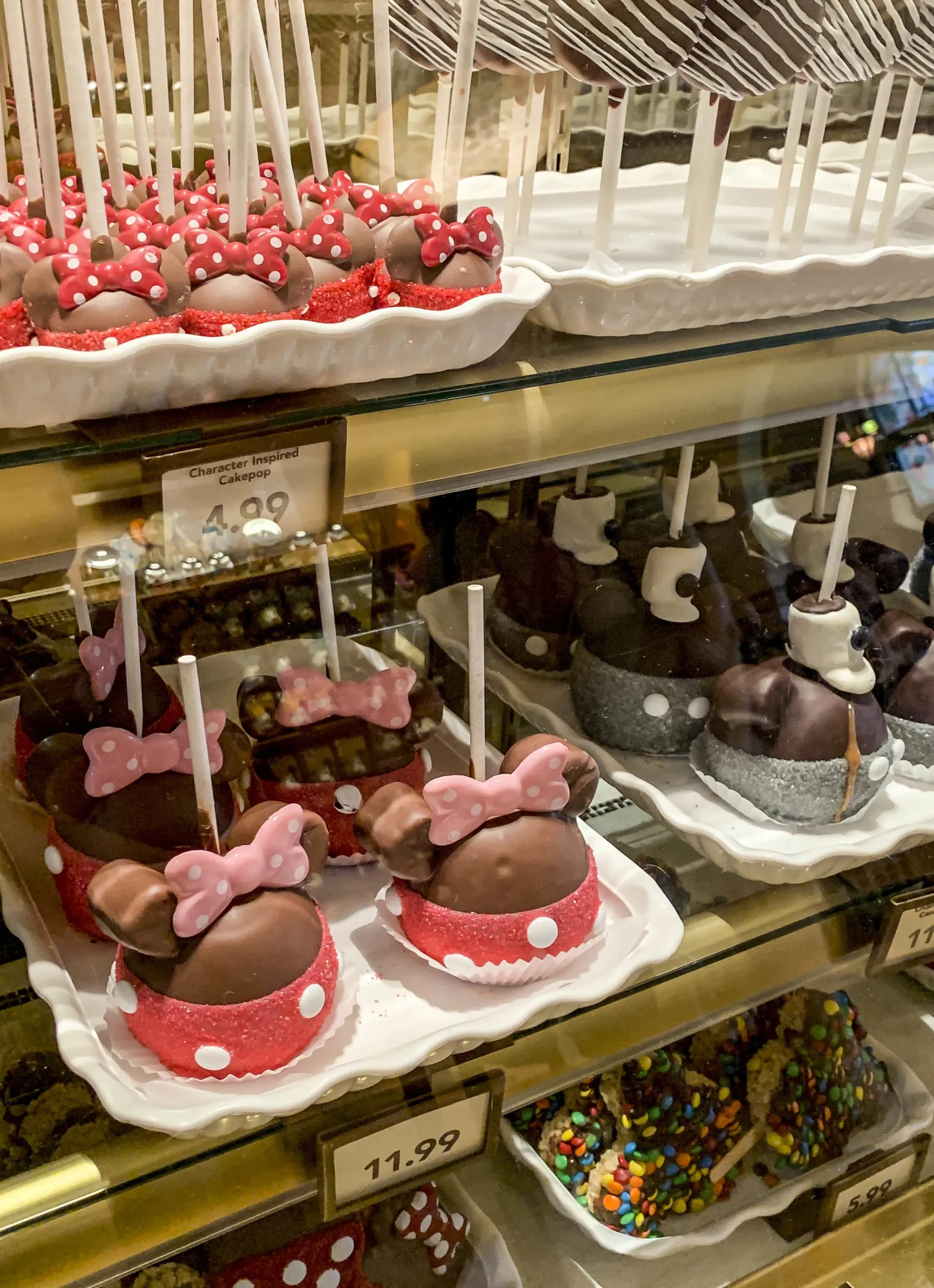Candy apples shaped like Minnie Mouse and other adorable desserts inside of a display case at Disneyland.