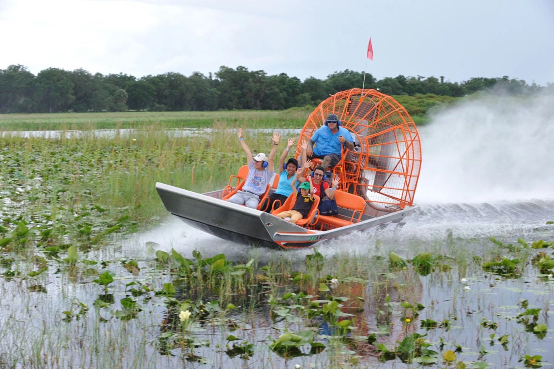 Guests ride an air boat through an everglade.