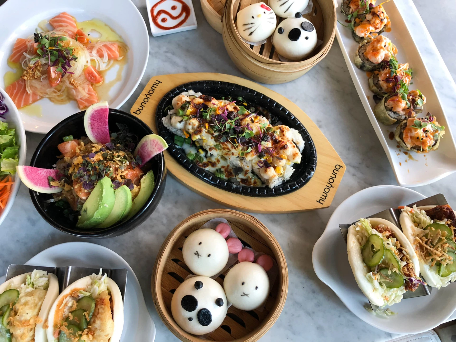 Character buns on a marble table with other Asian dishes at Harumama in San Diego.