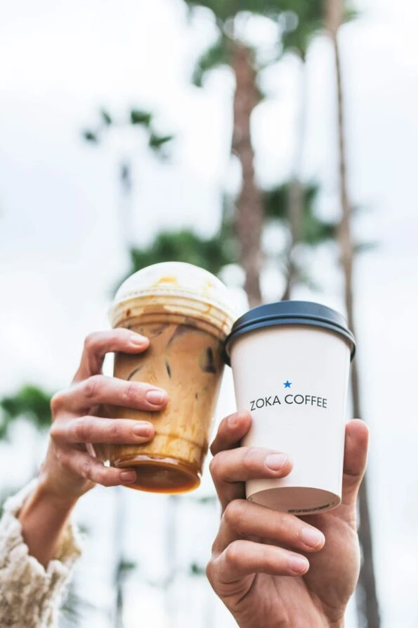 Two guests hold up gourmet coffee drinks from Aroma.