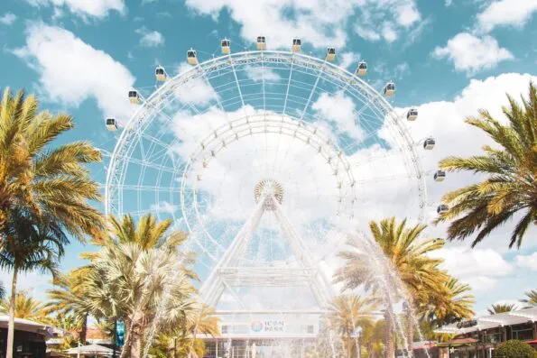 The Wheel at ICON Orlando spins against a blue sky with patches of clouds, one of the best things to do in Orlando with kids.
