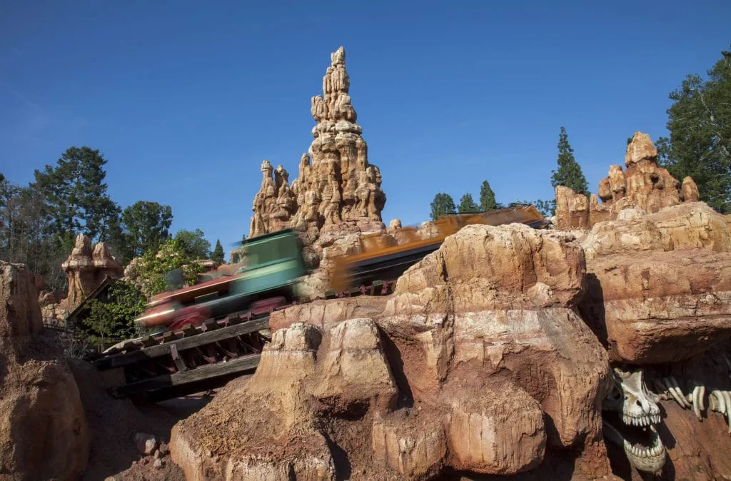 A Big Thunder Mountain Railroad train speeds past the red mountain.