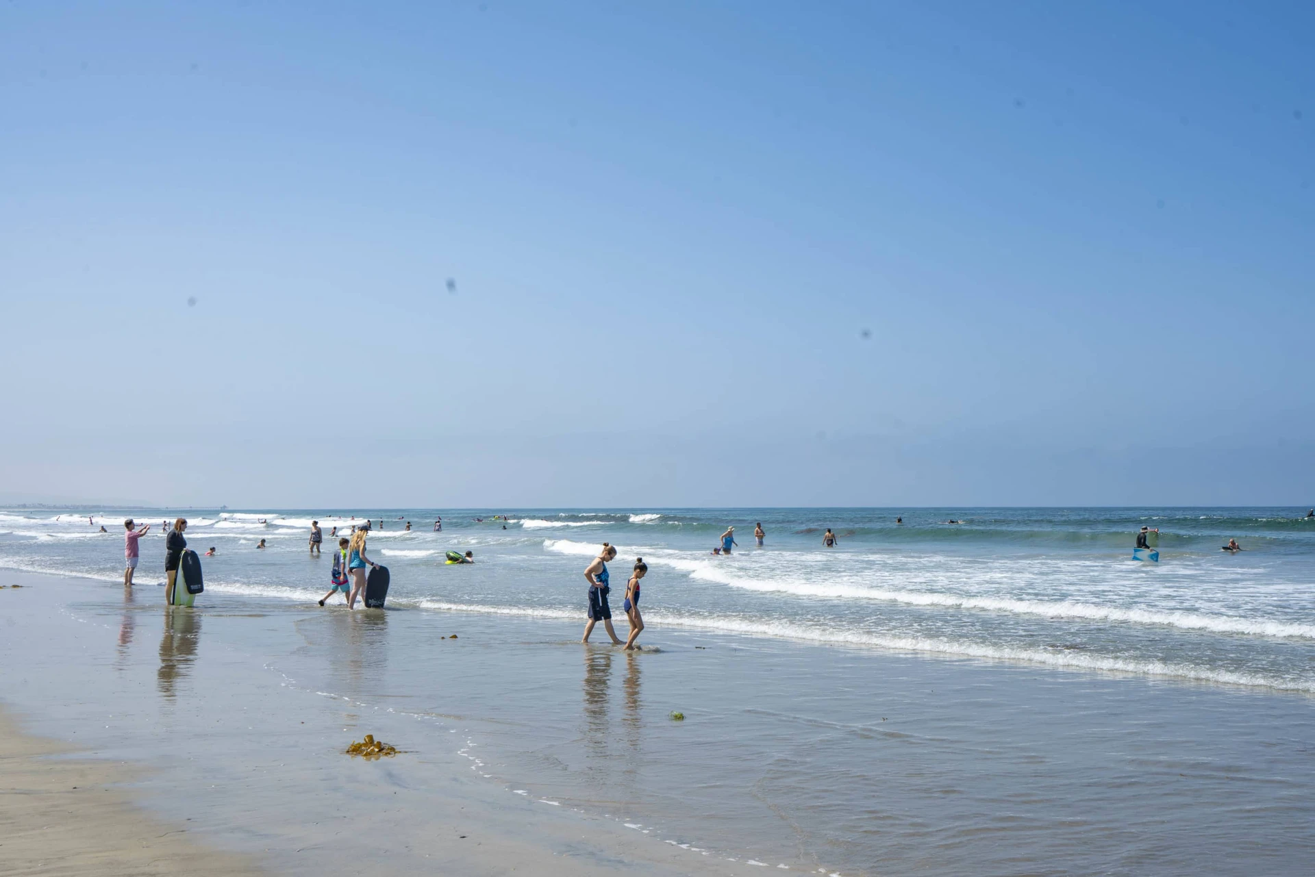 Families boogie boarding and playing at the water's edge at Silver Strand State Beach, a popular Coronado beach.