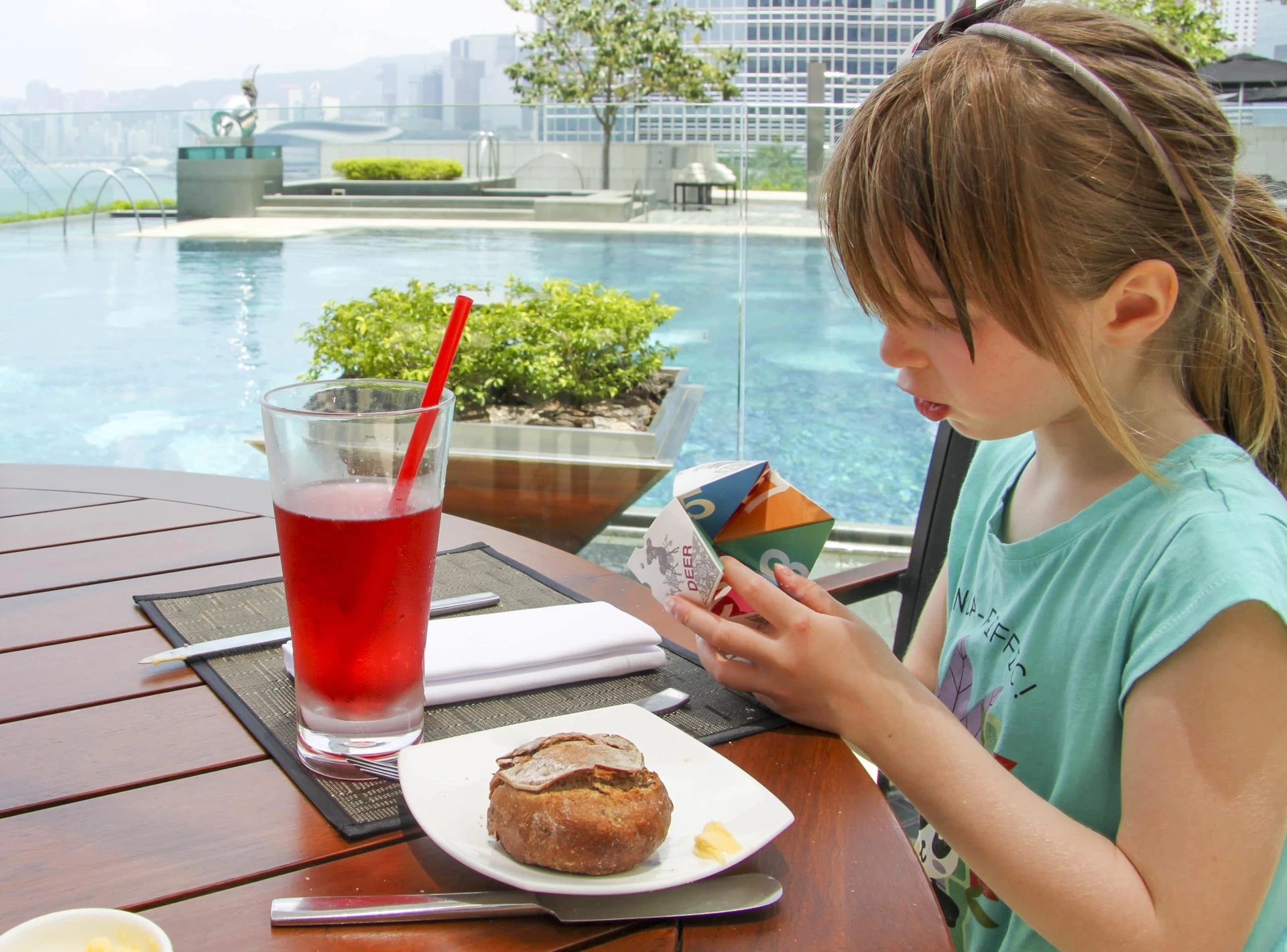 My daughter holds the paper fortune teller during lunch by the pool at Four Seasons Hong Kong.