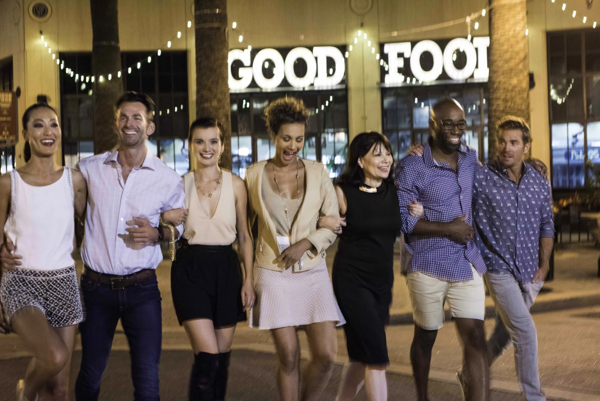 A group of friends walks arm in arm down Center Street Promenade in Anaheim.