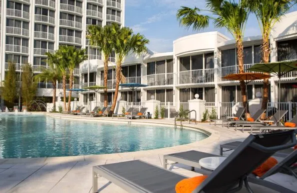 Pool area surrounded by grey lounge chairs with orange pillows at B Resort & Spa in Orlando.
