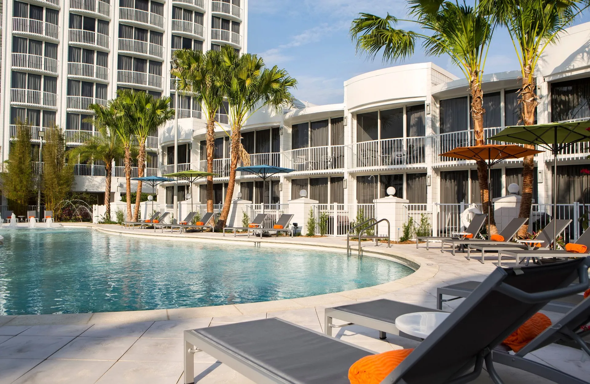 Pool area surrounded by grey lounge chairs with orange pillows at B Resort & Spa in Orlando.