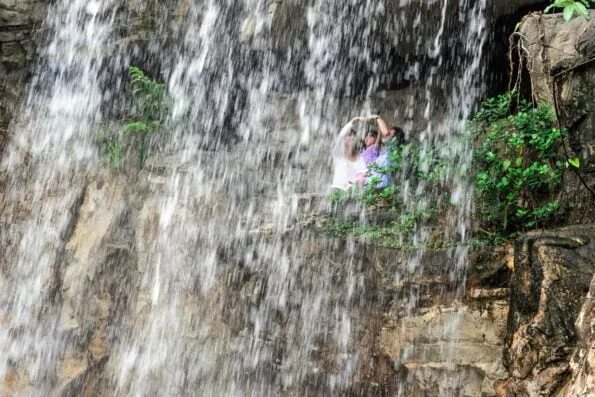 A family walks under the waterfall at Hong Kong Park.