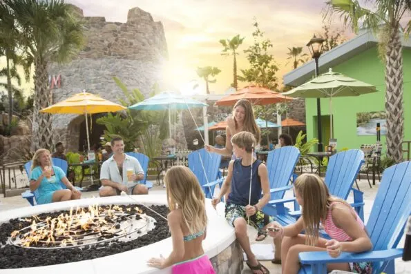 A family roasts s'mores on a fire pit outside at Loews Sapphire Falls.