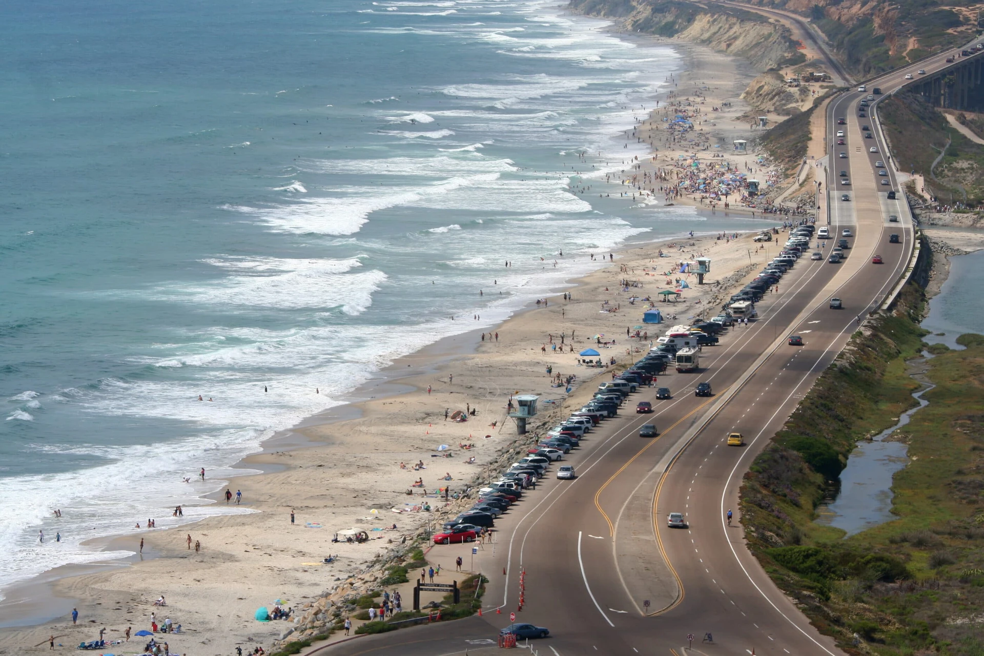 View of crowds enjoying Torrey Pines State Beach, a popular Del Mar Beach.