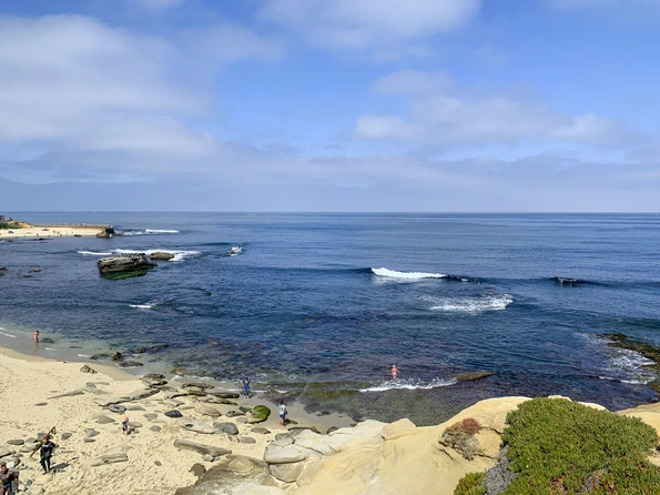 Beachgoers walk in shallow water on the rocks at Shell Beach, La Jolla.
