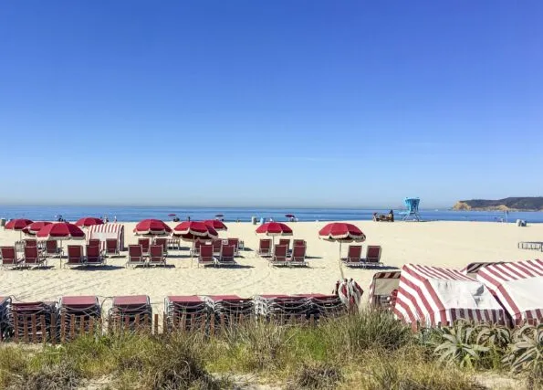 Red beach chairs in the sand in front of Hotel del Coronado.