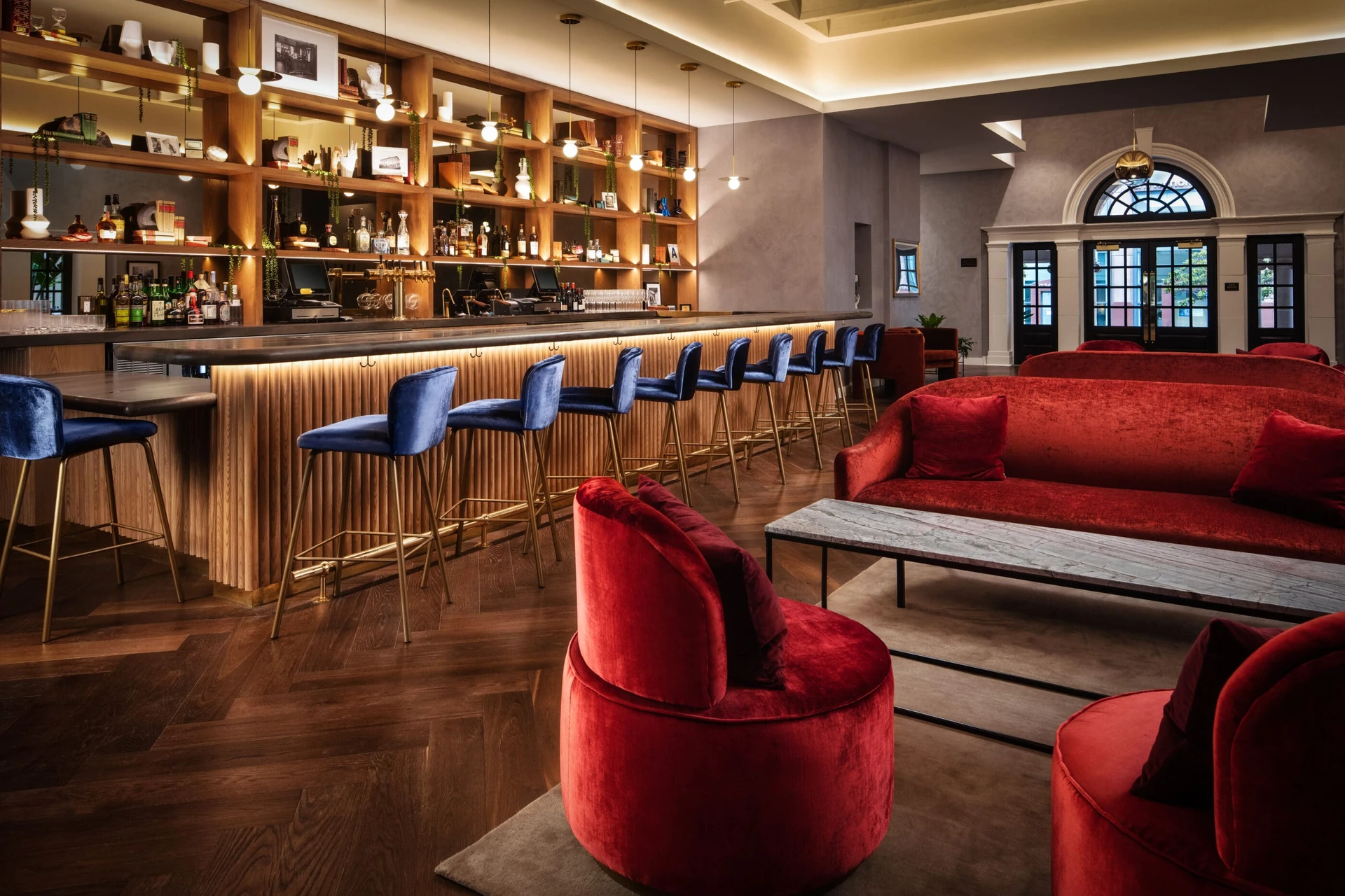 Red velvet couches and blue barstools in The Guild Bar.