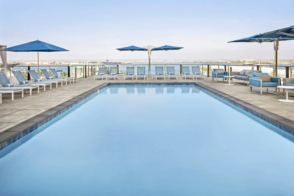 Open-air pool deck surrounded by lounge chairs, overlooking San Diego Bay.
