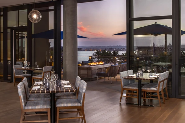 Tables in Vistal Restaurant overlook the San Diego Bay at sunset.