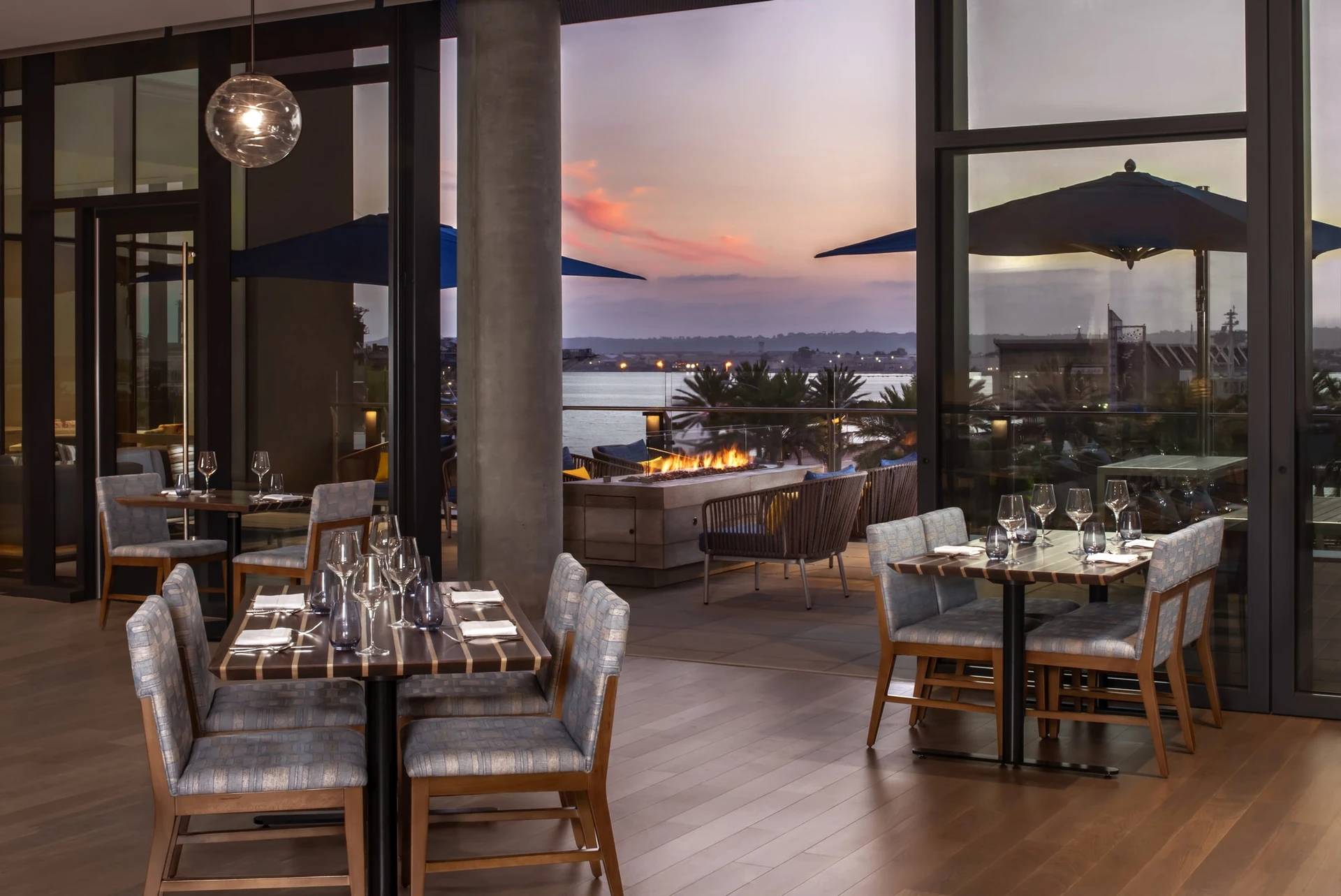 Tables in Vistal Restaurant overlook the San Diego Bay at sunset.