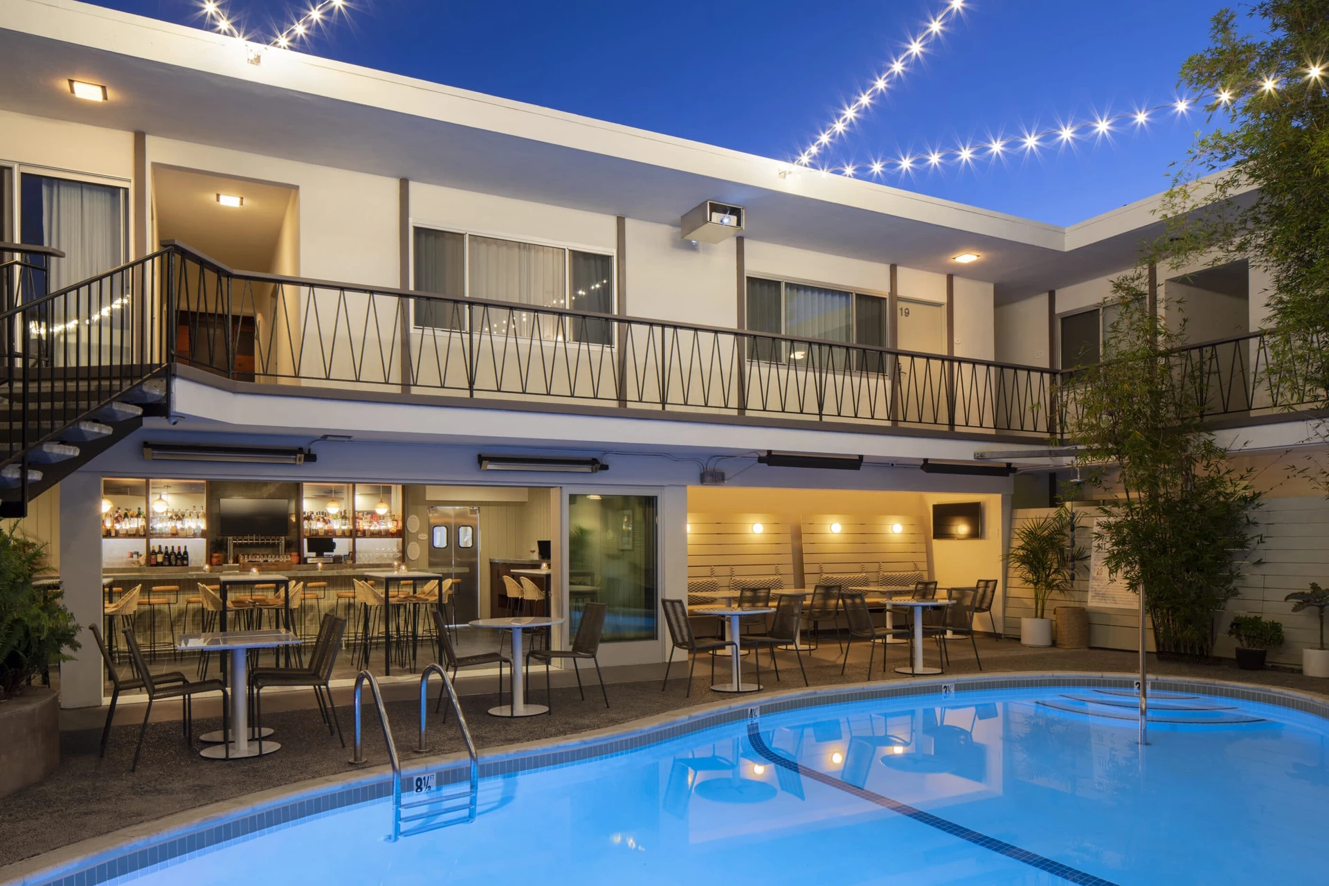 The Pearl Hotel pool with bar seating in the background at dusk.