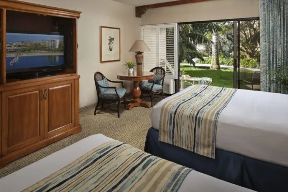 Interior view of a double queen Garden View room out to a grassy area.