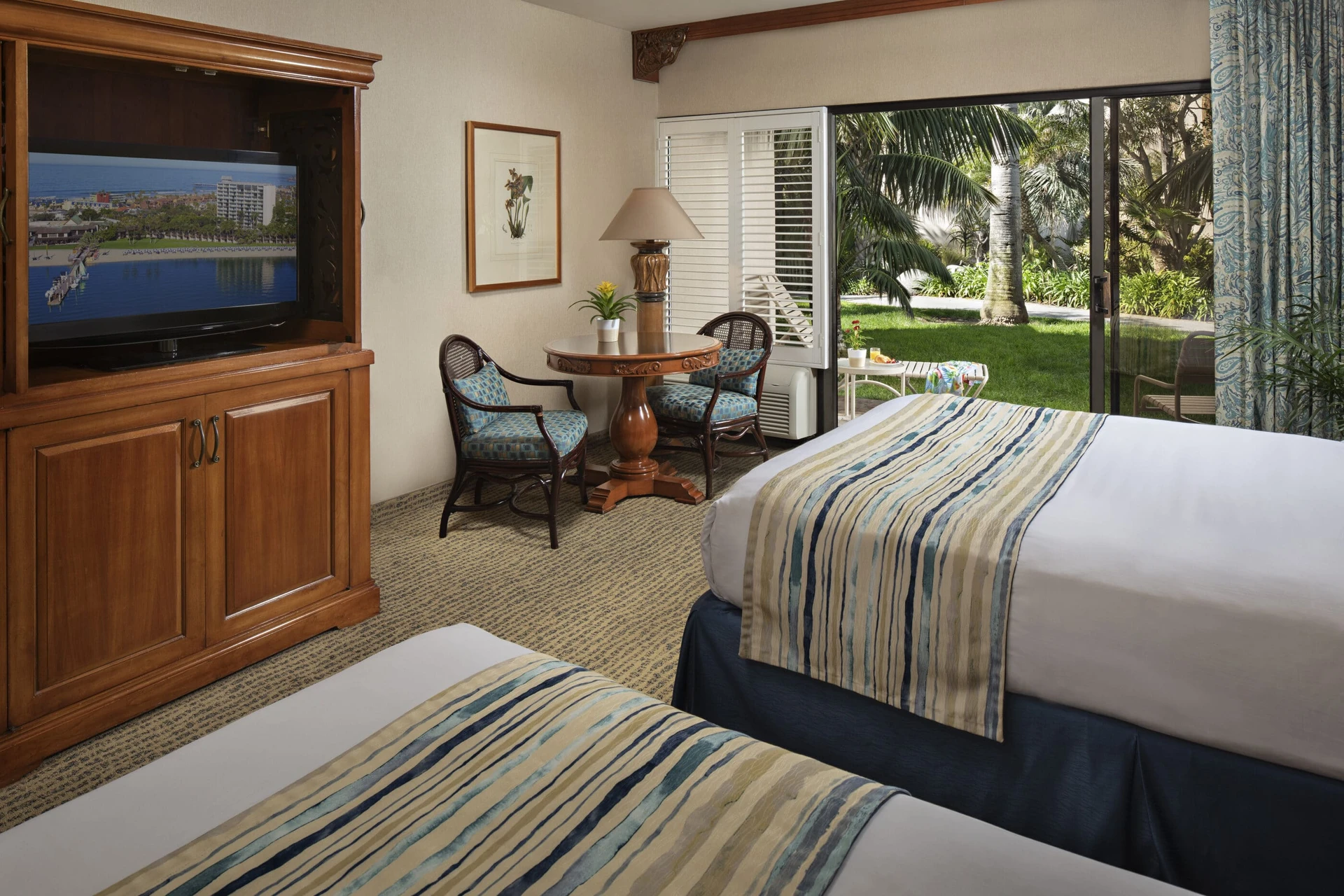 Interior view of a double queen Garden View room out to a grassy area.