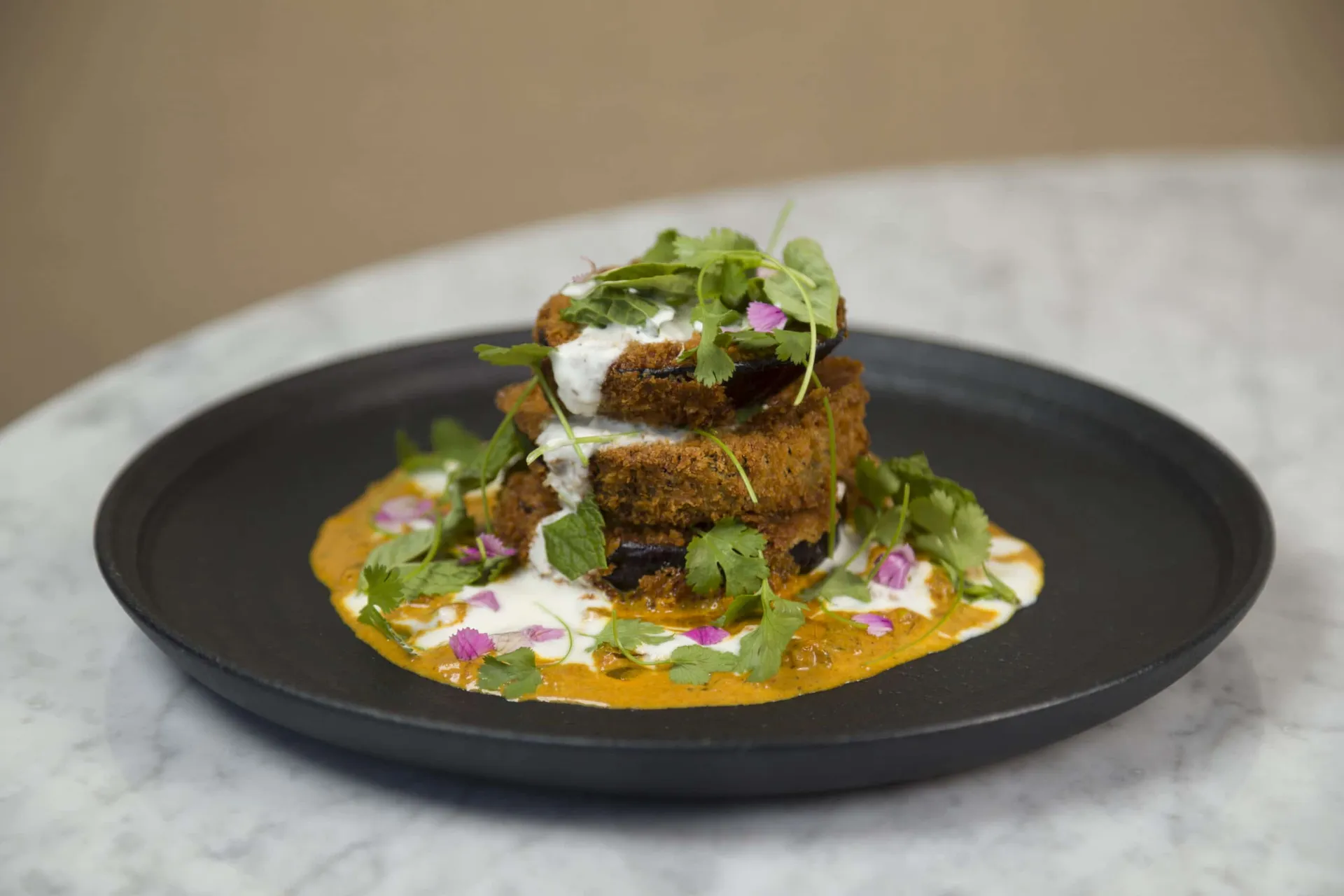 Eggplant tikka masala on a black plate.