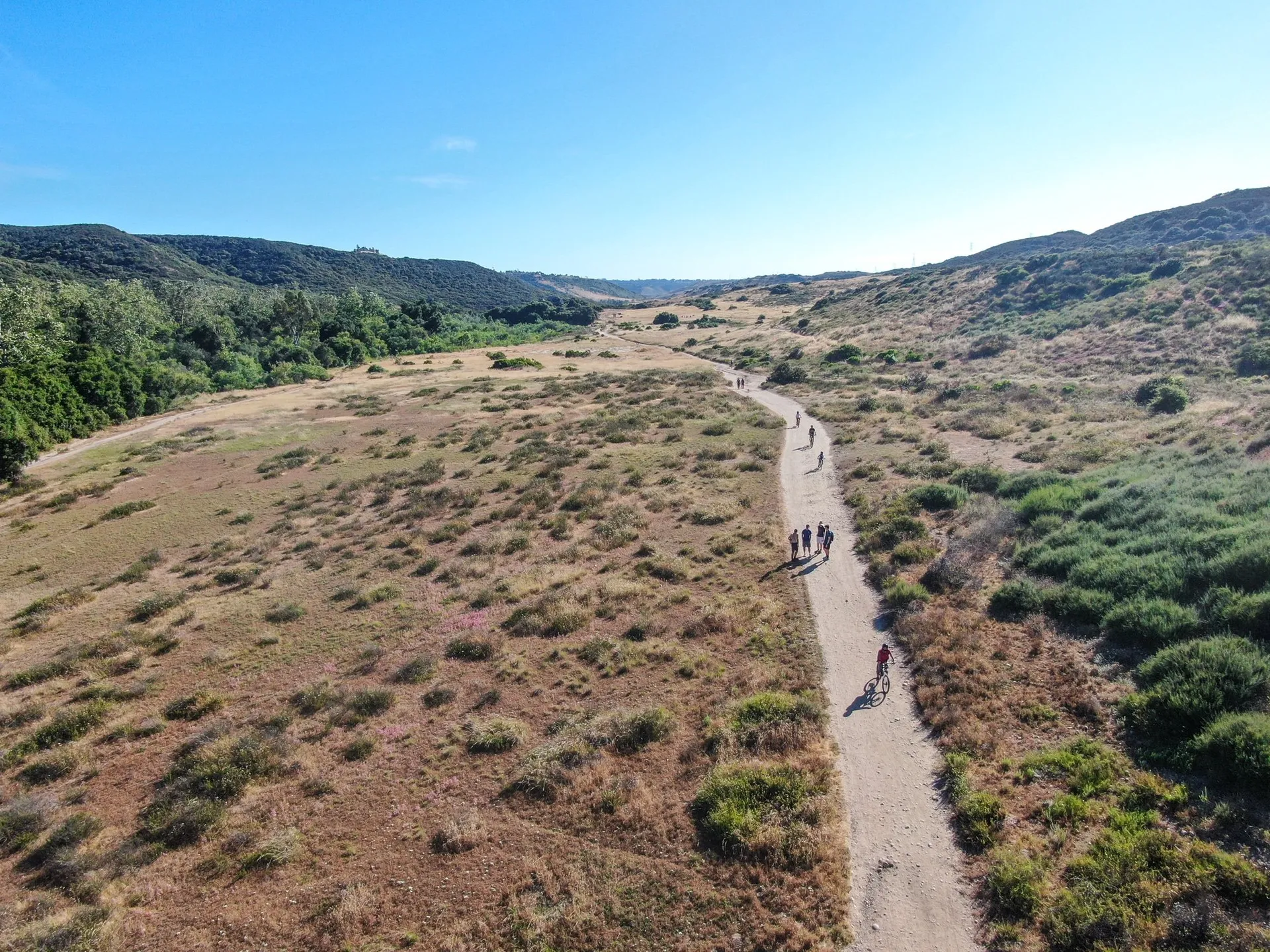 Aerial view of hikers and bikers on the Los Penasquitos Trail on a sunny day.