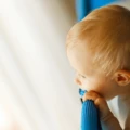 A baby looks out from a travel crib.