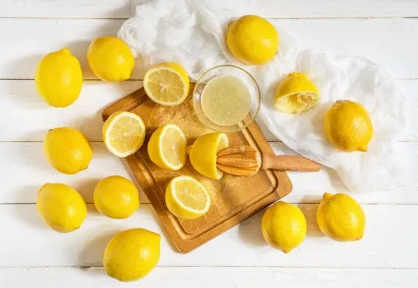 Halved and whole lemons on a table with a citrus reamer.