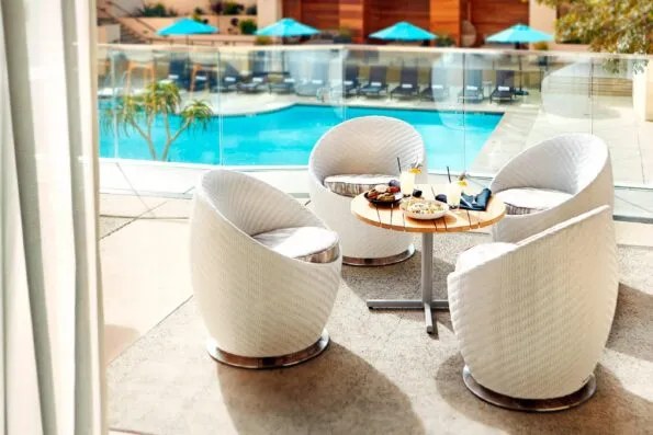 A seating area with food and drinks on the table near the outdoor swimming pool.