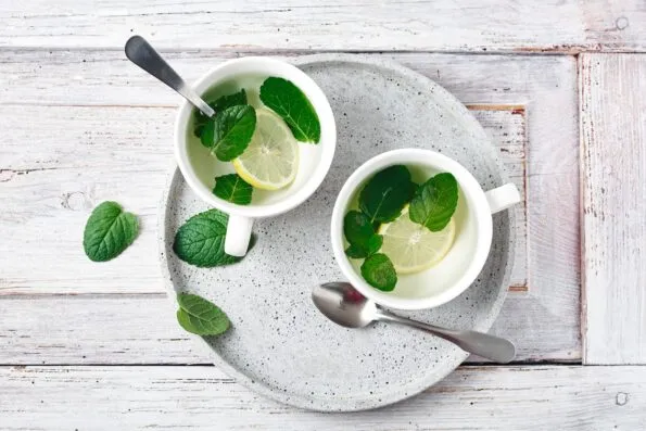 Fresh mint added to two cups of hot lemon water.