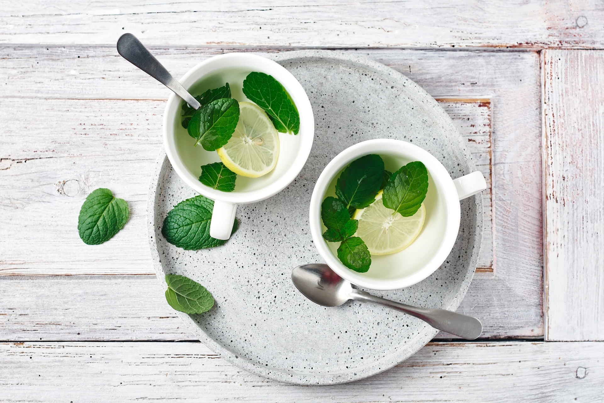 Fresh mint added to two cups of hot lemon water.