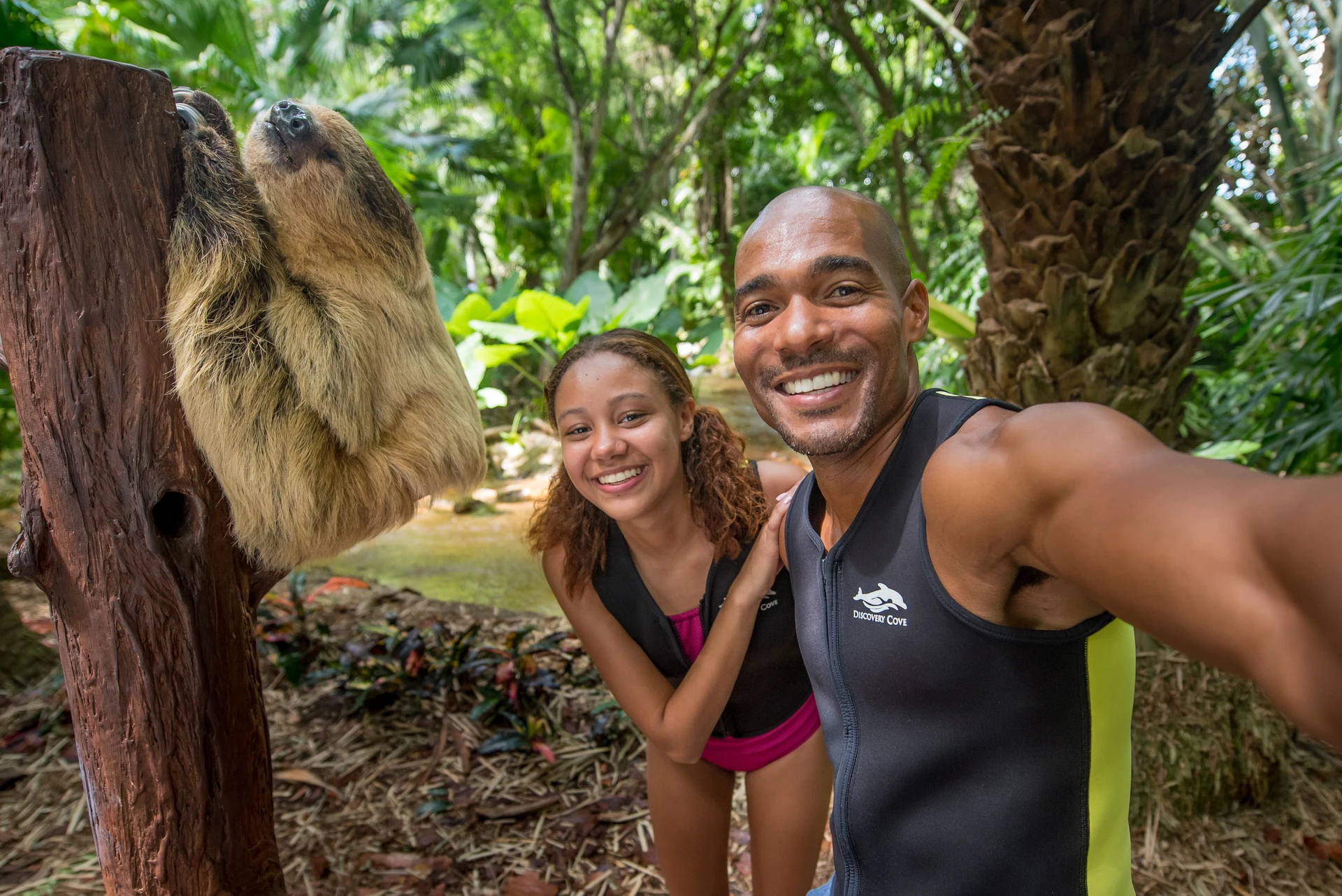 A couple takes a selfie with a sloth on Animal Trek.