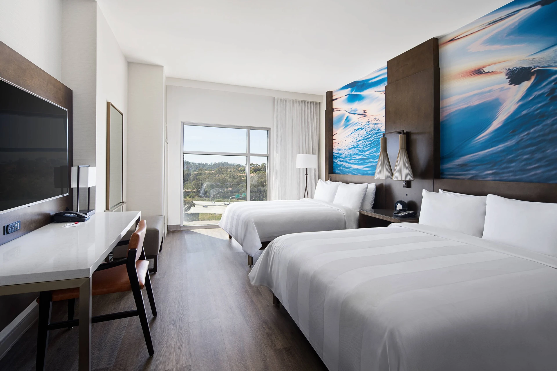 A two bed room interior with white sheets and coastal murals.