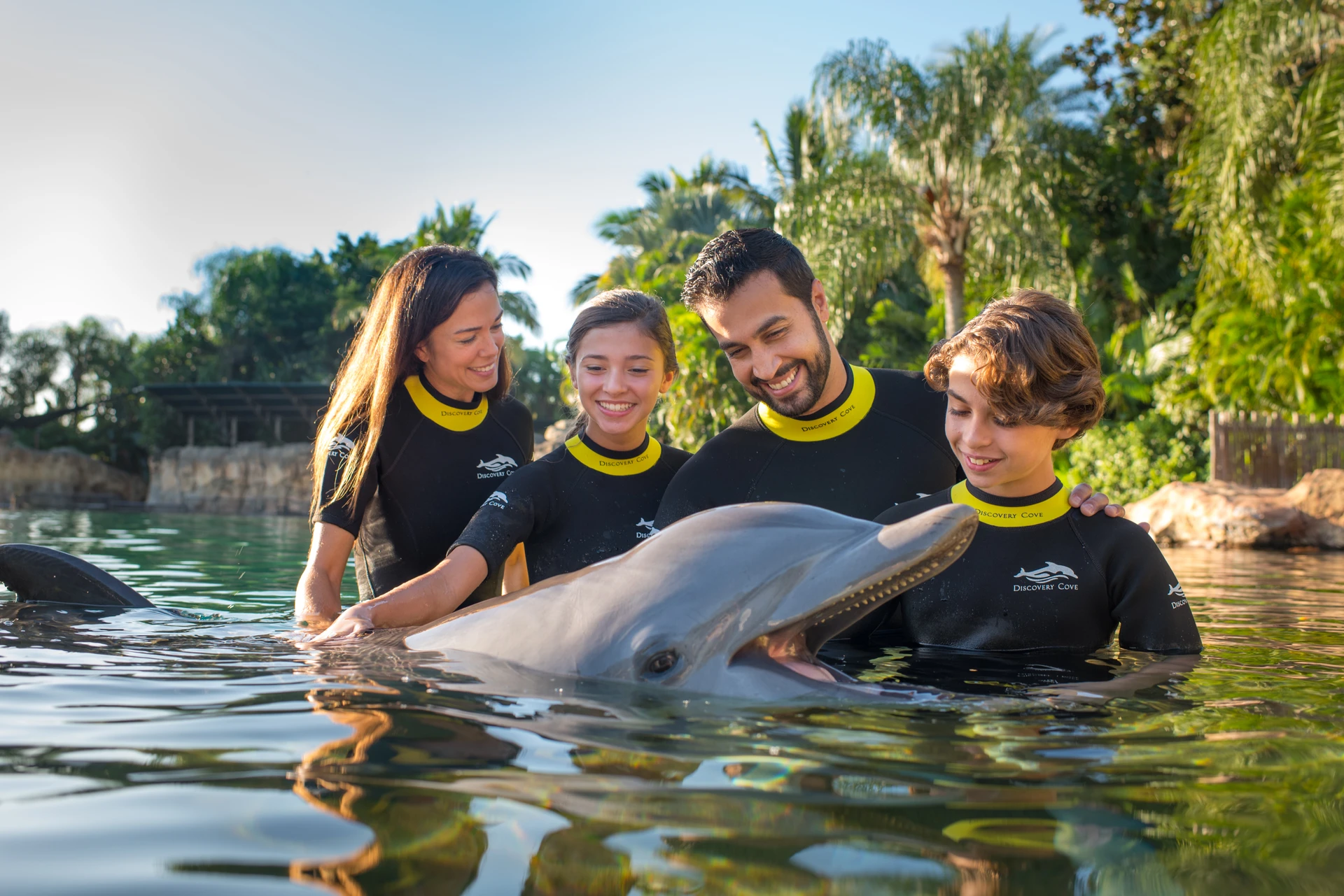 A family poses with a bottlenose dolphin in the water at Discovery Cove.