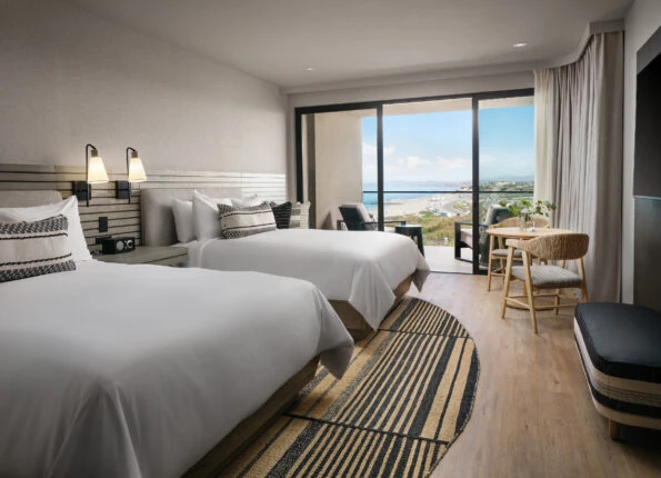 Two queen bed coastline view guest room interior.