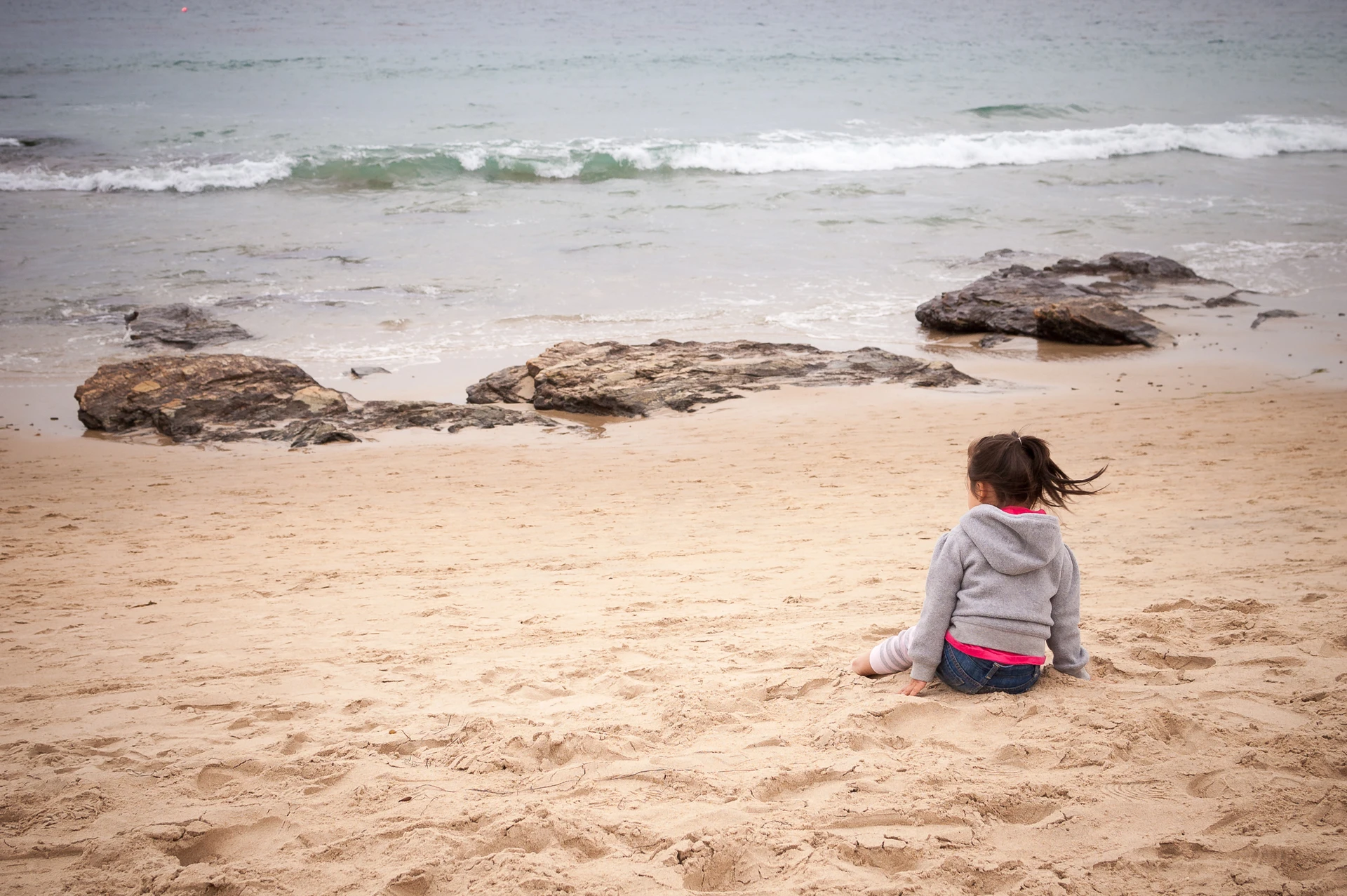 A little girl sits on the beach at Crystal Cove State Park.
