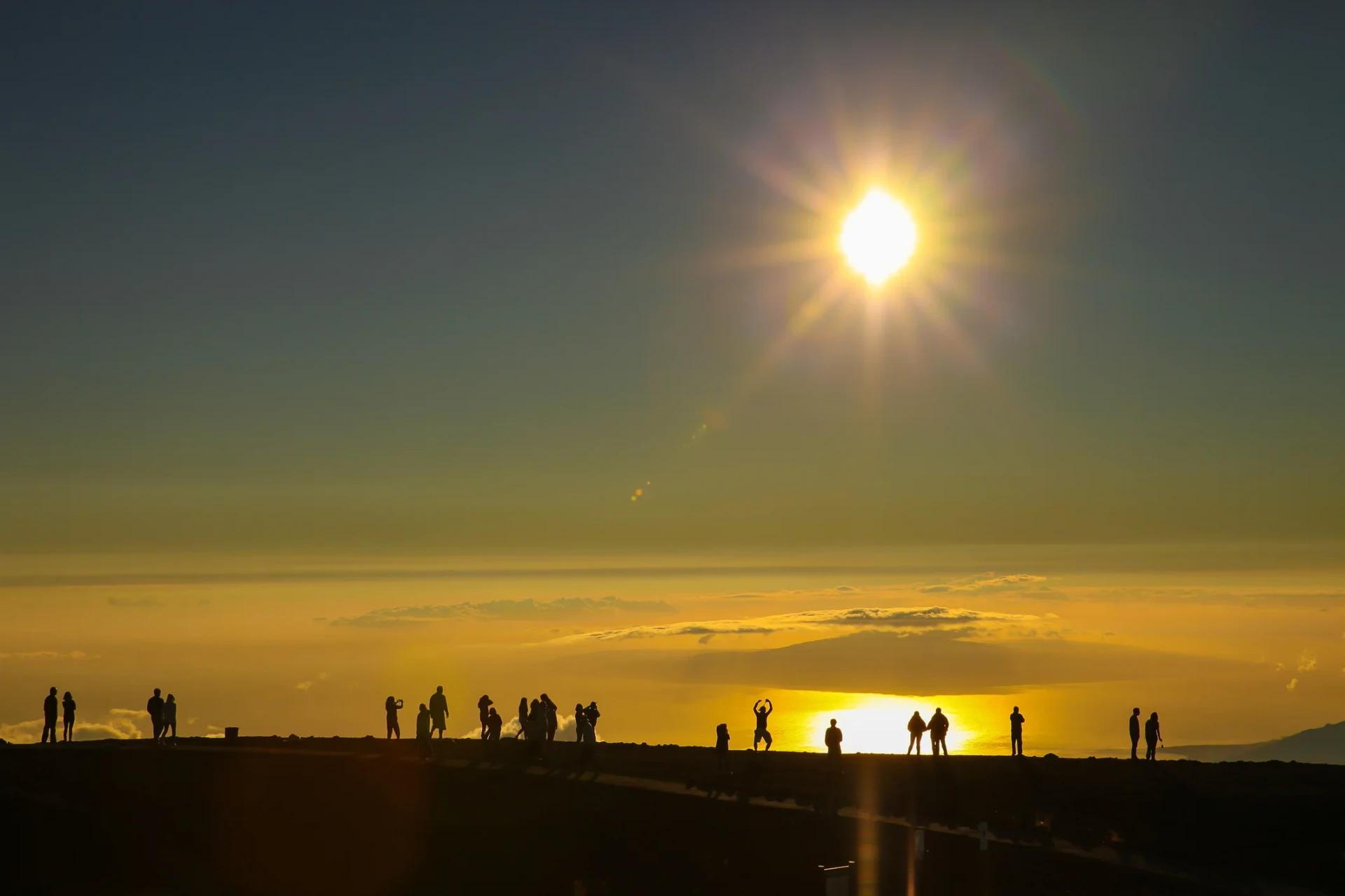 People stand on a ridge to enjoy the sunrise from Haleakala.
