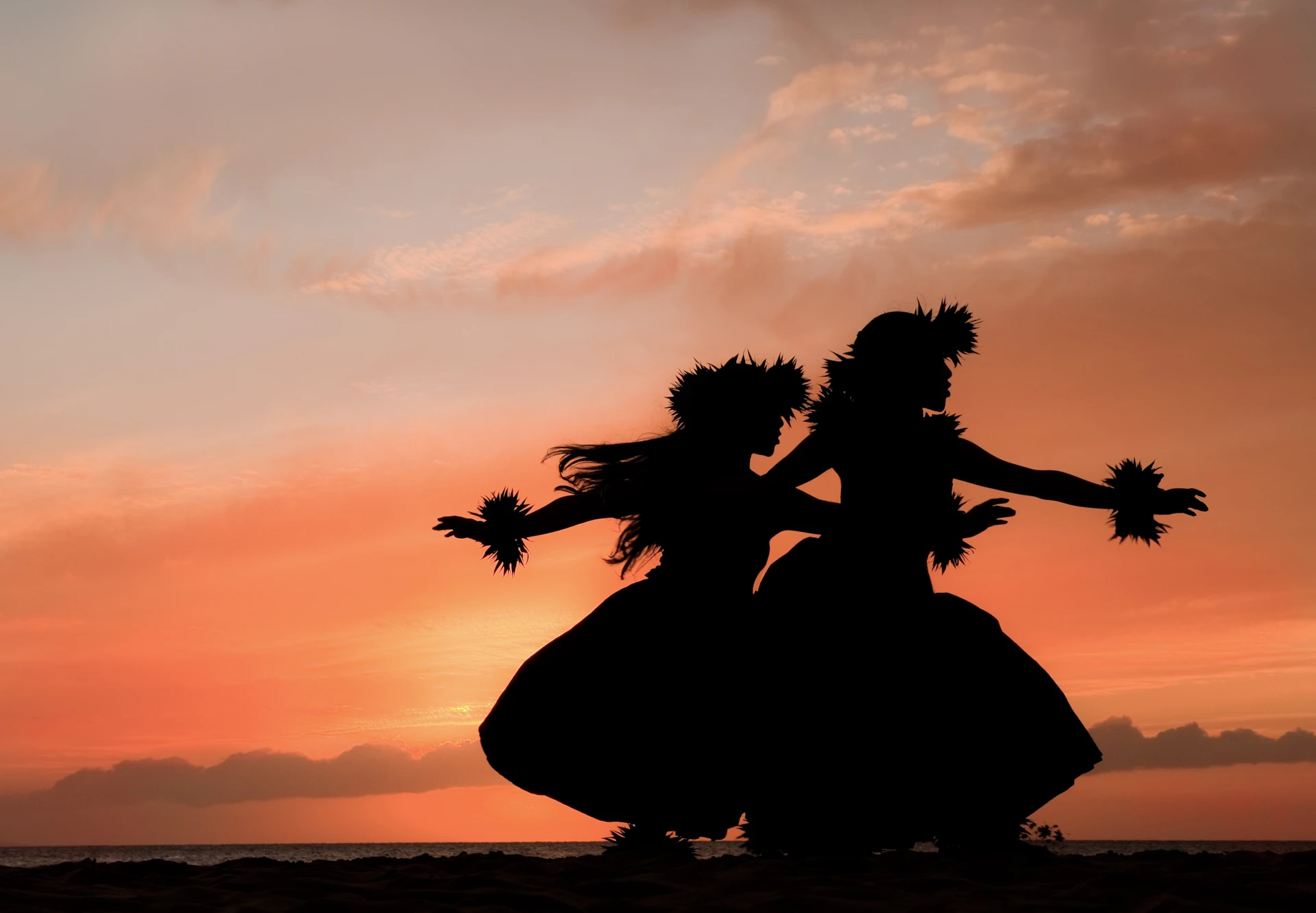 Shadow of two hula dancers against a glowing tropical sunset in Maui.