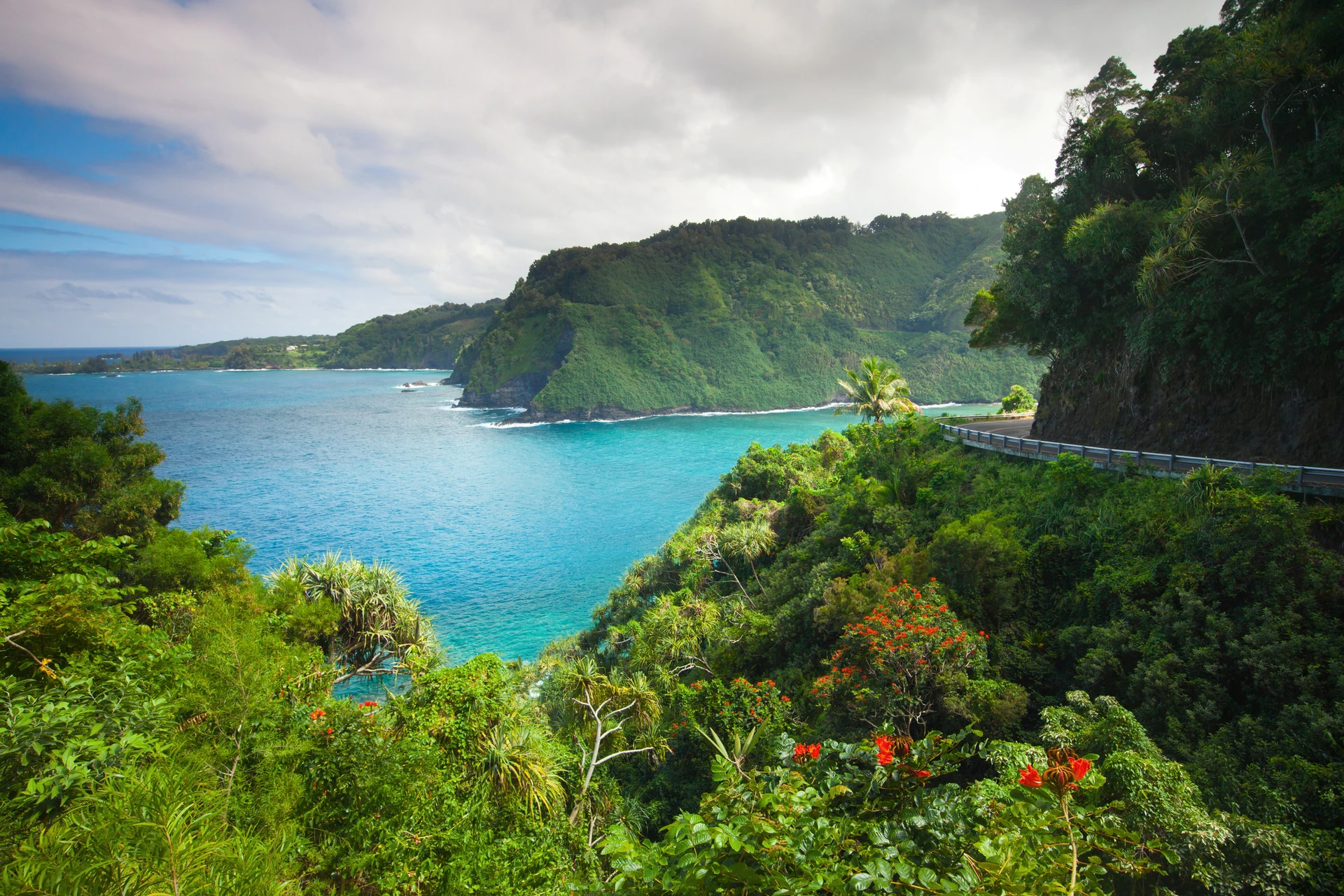 A narrow part of the road to Hana hugs the cliffside near the ocean.
