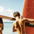 Two kids carry surfboards on a beach in Maui.