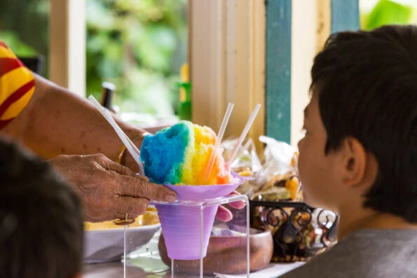 A boy is served a colorful shave ice.
