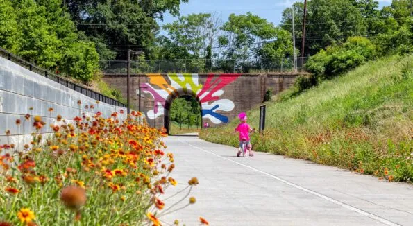 A little girl rides a bike toward a tunnel on The Atlanta Beltline.