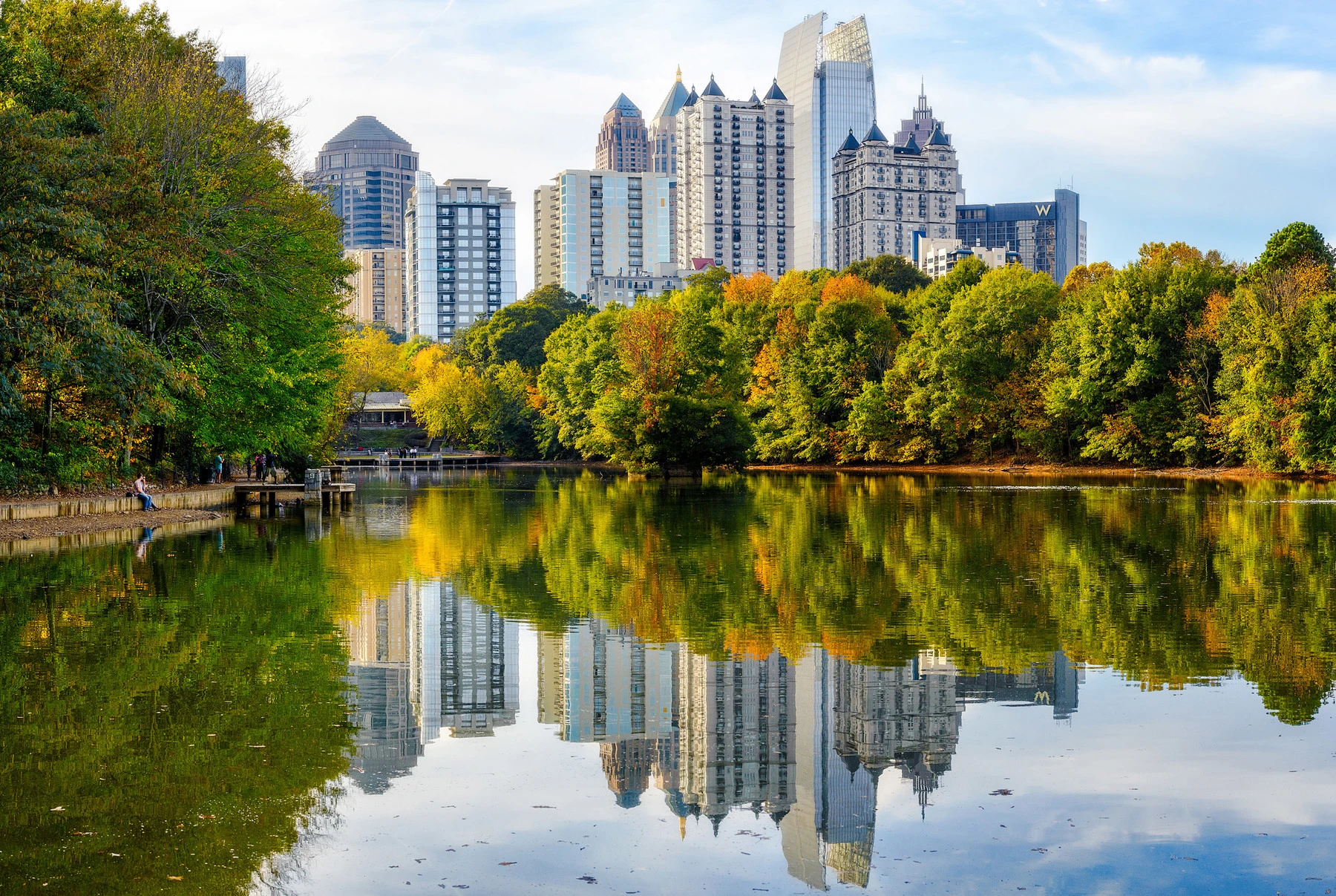 Midtown Atlanta buildings reflect off a lake at Piedmont Park.