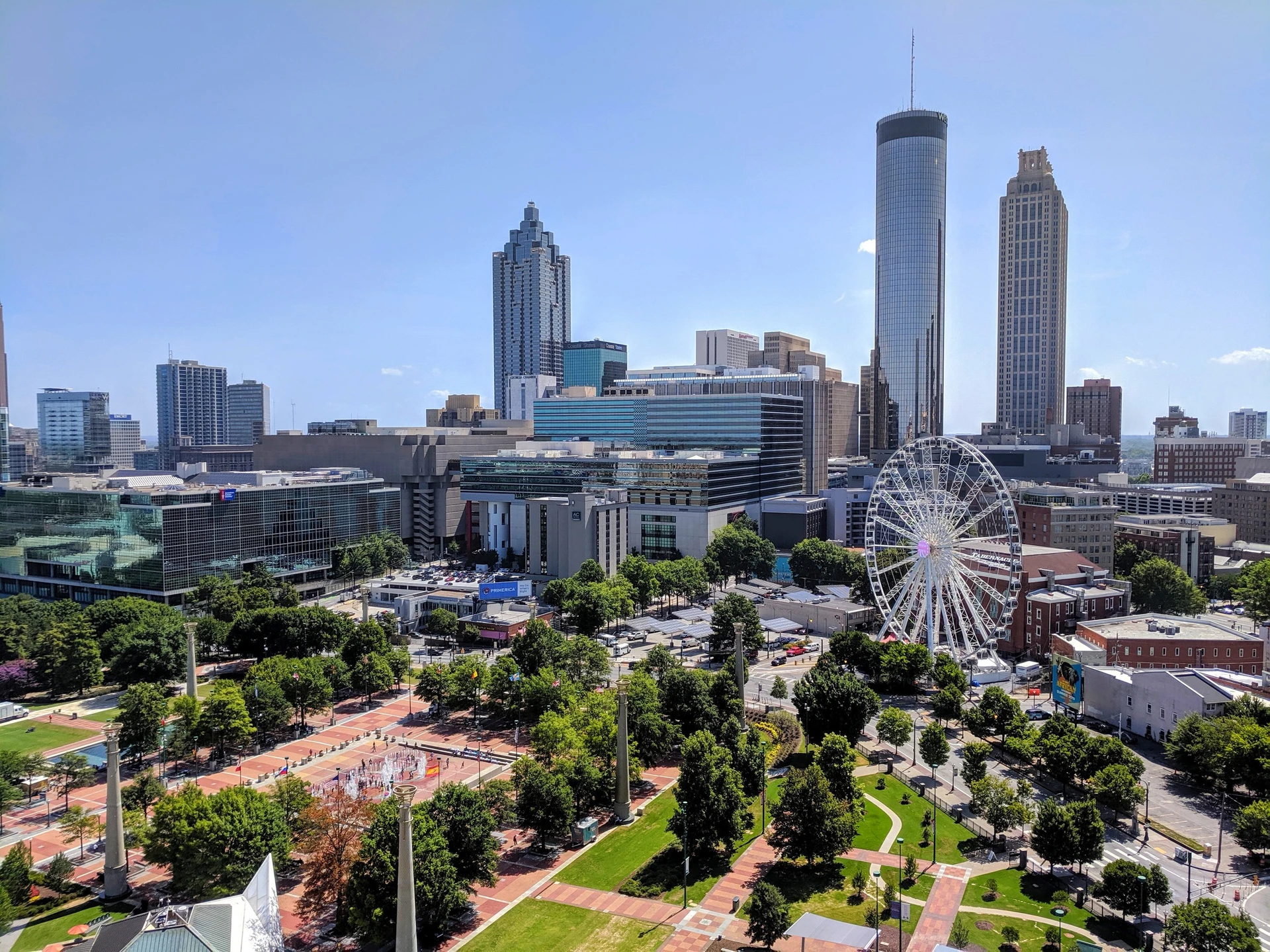 Aerial view of Centennial Olympic Park and Ferris Wheel with skyscrapers in the background.