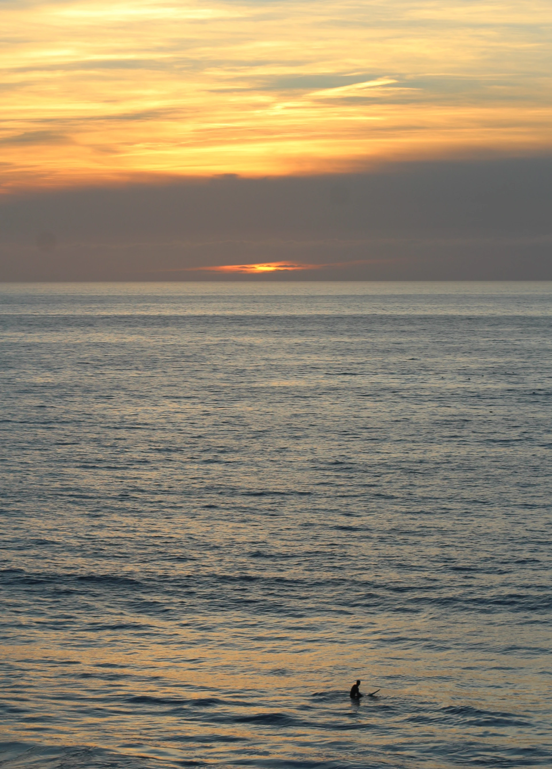 A surfer waits for waves at sunset at D Street Beach in Encinitas.