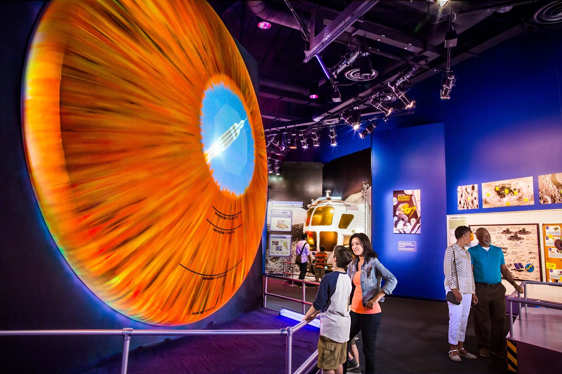 A woman and child look at the huge Orion heat shield display at Kennedy Space Center.