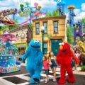 Elmo and Cookie monster walk with two girls through Sesame Place San Diego.
