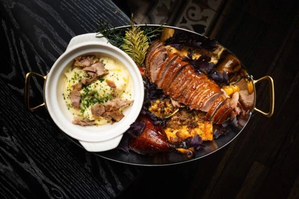 Half a roasted duck and stuffing cast iron plate for Christmas dinner in San Diego at Lionfish.